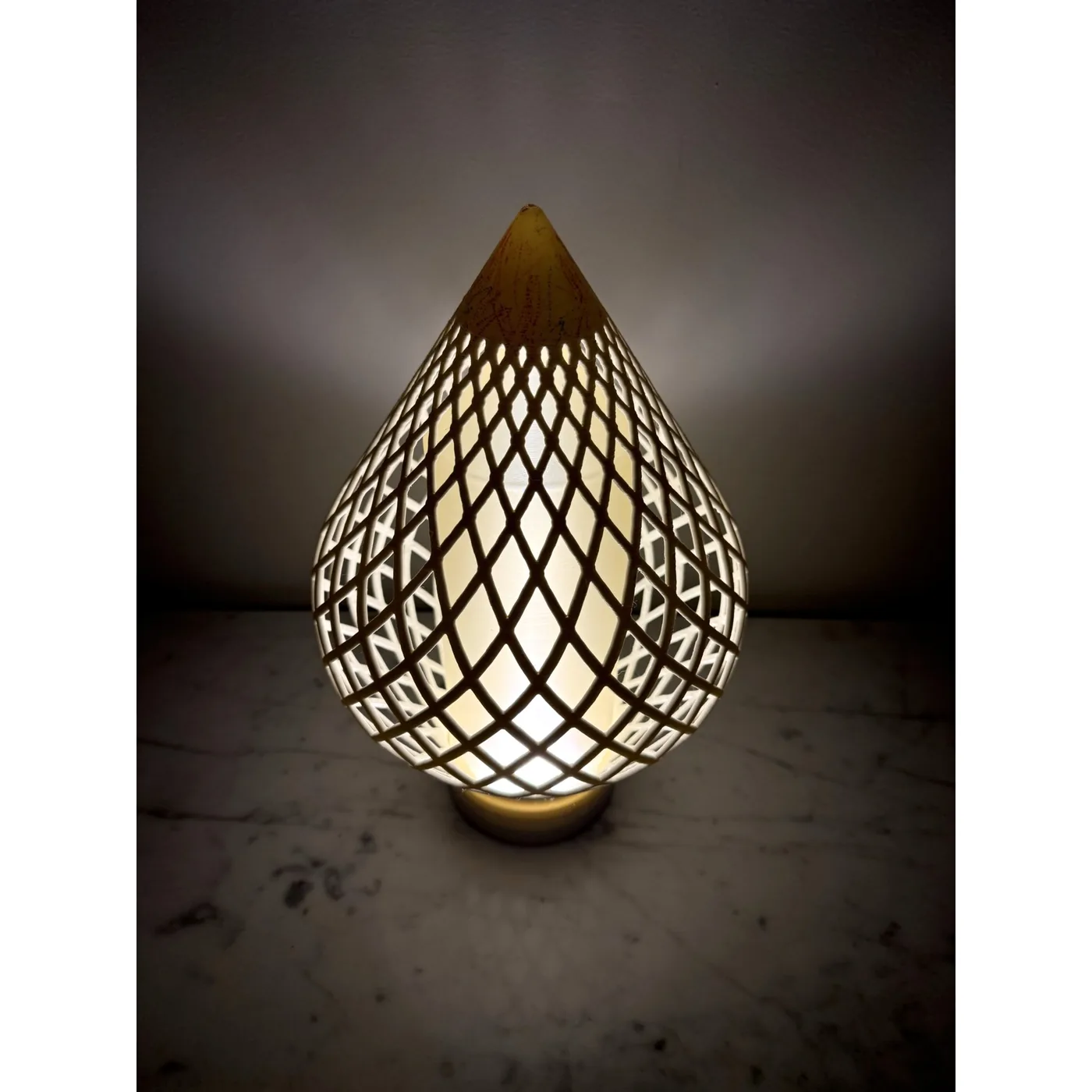Reef Diagrid lit in a dark room, the woven diamond shell glowing over its frosted core